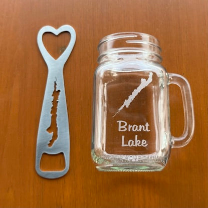 Brant Lake Clear glass handled mason jar with the silhouette of Brant Lake etched on it and Brant Lake text below the lake. This gift set also inlcudes a stainless silhouette of Brant Lake Bottle opener.