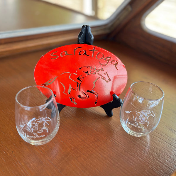 Red Metal Saratoga with a horse cutout trivet paired with two clear glasss stemless wine glasses.