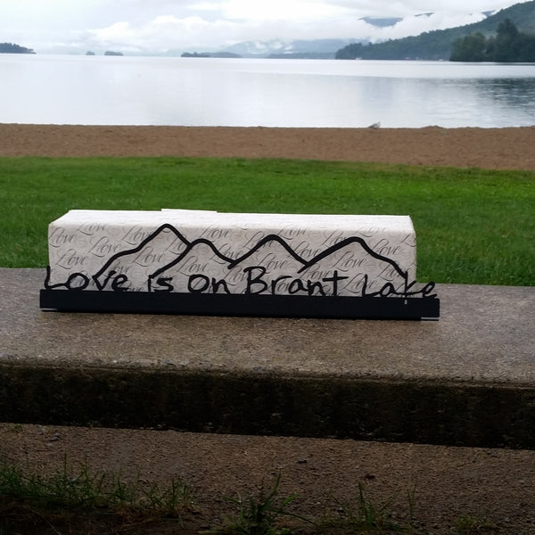 Love is on Brant Lake text on a metal sign with the cutout of the Mountains; graphite.