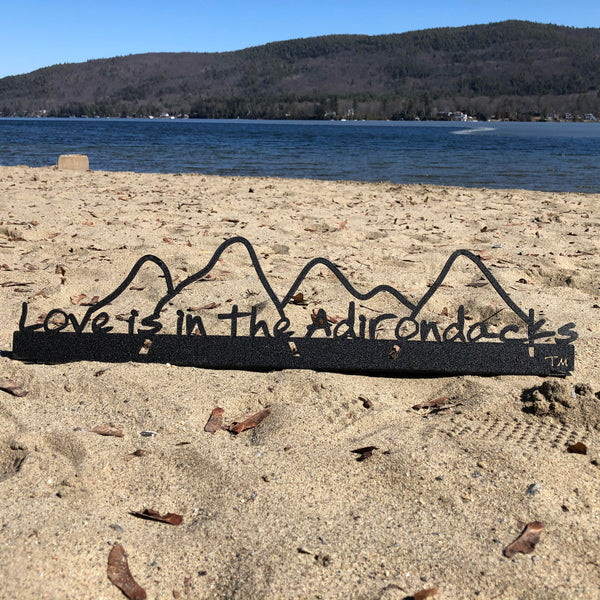 Love is in the Adirondacks text on a stainless steel shelf sitter with the mountains.