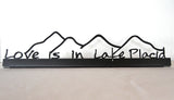 Love is in Lake Placid text on a metal sign sitter with the Adirondack mountains; color black