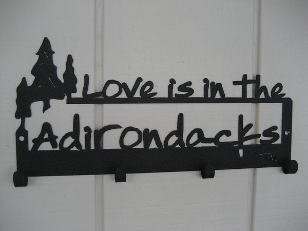 Love is in the Adirondacks text with a cluster of 3 pine trees on a 4 hook wall mount.