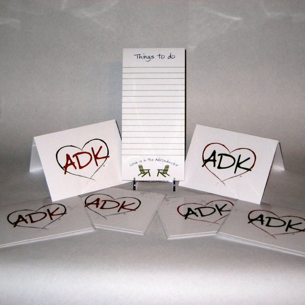 Things to do notepad text on top of each sheet with Love is in the Adirondacks arched over two opposing Adirondack Chairs. Adirondacks note cards have our interlocking Love is in the Adirondacks ADK Heart silhouette in alternating colors; red/green