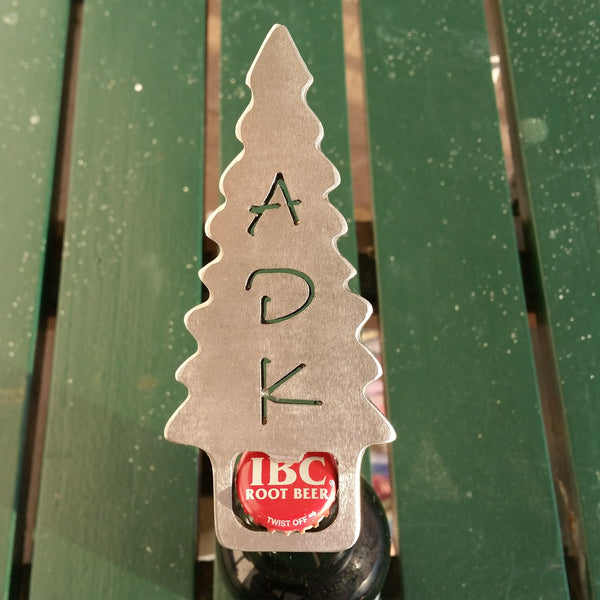 Handcrafted stainless steel bottle opener with a ADK cut out of an Adirondack evergreen tree. The bottle opener tab is at the base of the tree.