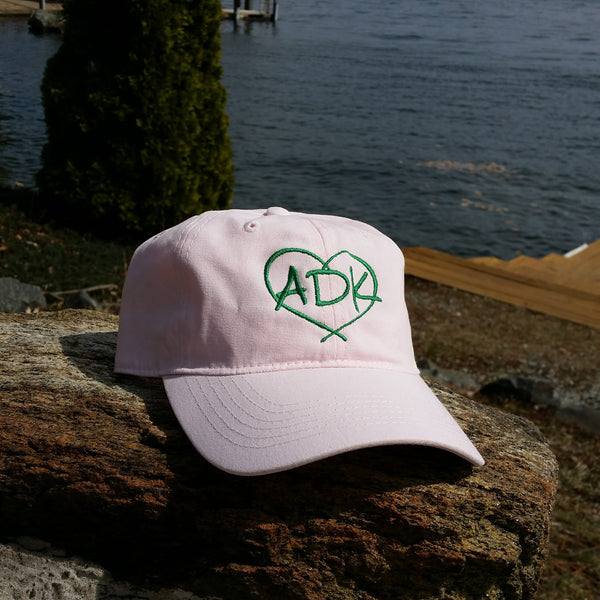 Ball cap with our ADK in a heart silhouette logo. Pink hat with green embroidery..