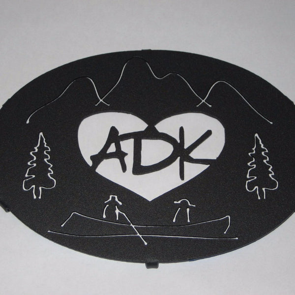 ADK in a heart with the Adirondack mountains, trees and guide boat. It is powder coated graphite. It is 8" x 6".