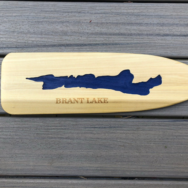 Silhouette of Brant Lake etched on a wood paddle blade and painted blue. BRANT LAKE text below the lake silhouette