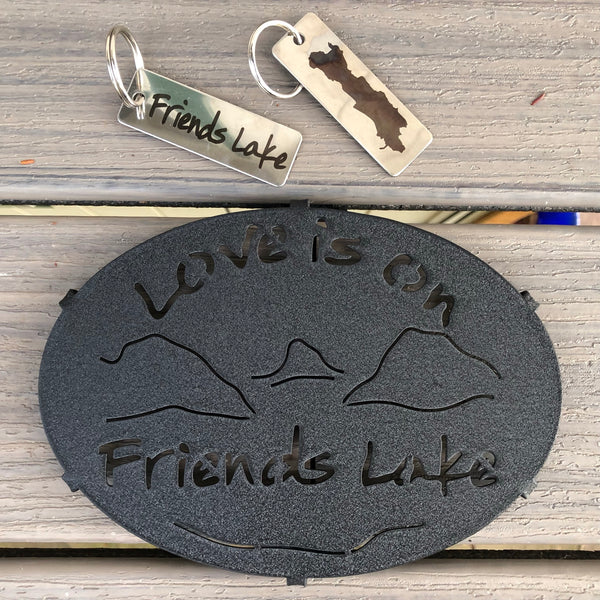 Love is on Friends Lake text on a metal trivet with a lake and mountain scape. Stainless Key chain with the silhouette of Friends Lake on one side and Friends Lake text on the other side.