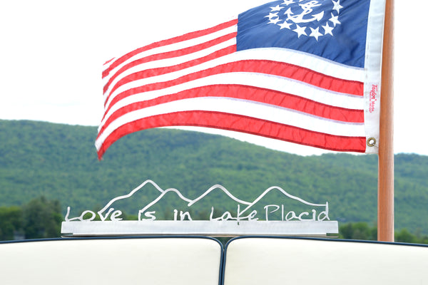 Love is in Lake Placid text on a stainless sign with Mountains.