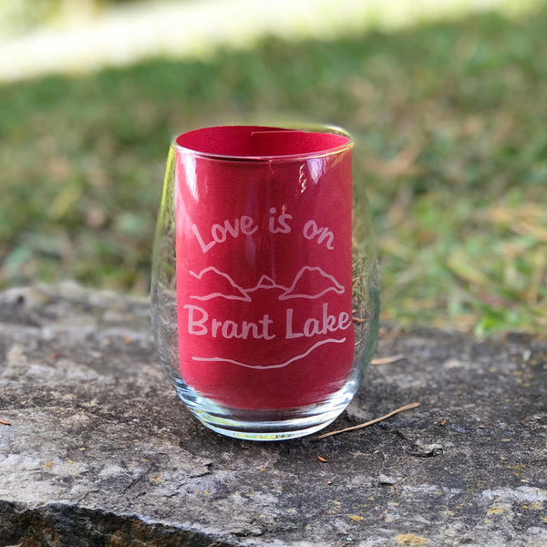 Clear stemless wine glass with a lake and mountain scene. Text reads Love is on Brant Lake