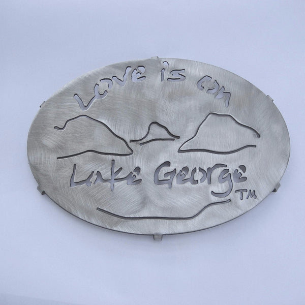 Love is on Lake George text above and below a lake and mountain scene on a stainless trivet.