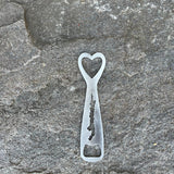 SIlhouette of Brant Lake cut out on a stainless bottle opener with a heart cut out at the top.