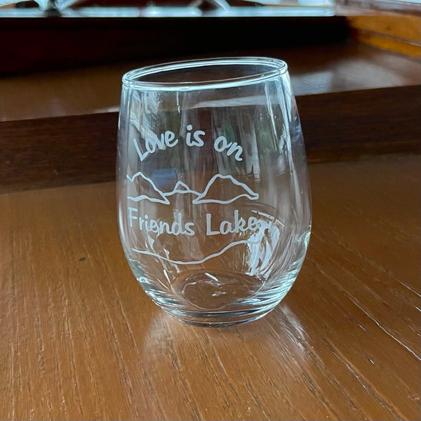 Love is on Friends Lake text over/under mountain and lake scene on a clear glass.