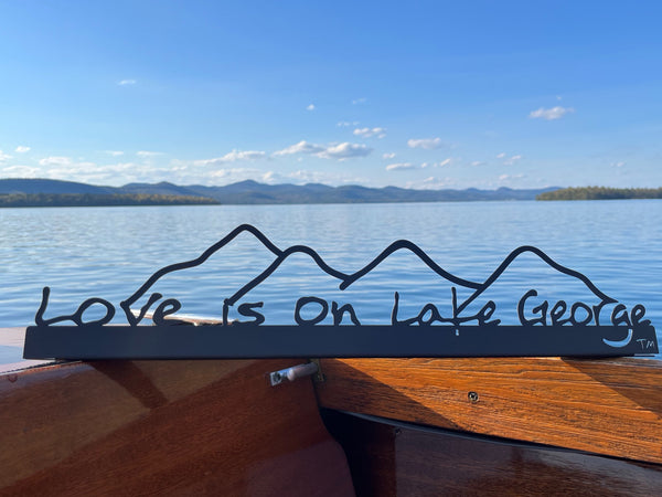 Love is on Lake George text on a metal sign with the cutout of the Mountains; graphite . 