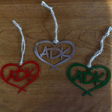 3 Adirondack metal ornaments.  The design in ADK in a heart with a hand tied  twine hanger.  The set includes a red, green and stainless ornament.
