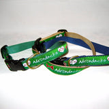 Dog collar with our ADK in a heart logo, a dog bone and the Adirondacks on a ribbon with webbing on the other side of the dog collar