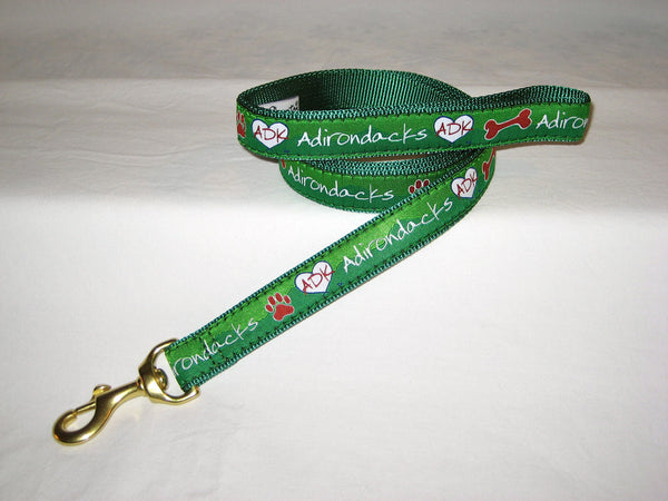 Adirondack Dog leash with our ADK in a heart logo, a dog bone, paw and the Adirondacks on a ribbon with webbing on the other side of the dog leash; comfort fleece handle; color green