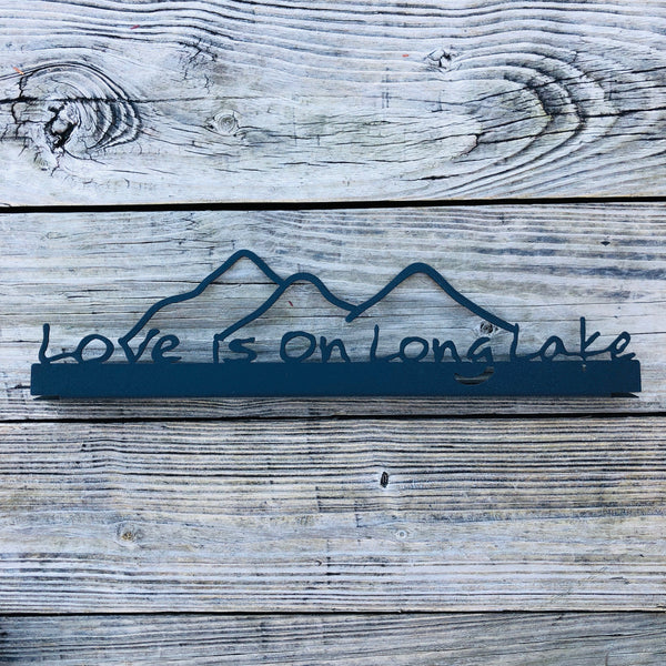 Love is on Long Lake text on a black metal shelf sitter with 3 mountains peaks.