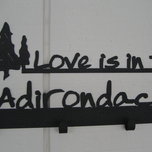 Love is in the Adirondacks text with a cluster of 3 pine trees on a 4 hook wall mount.