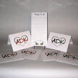 Things to do notepad text on top of each sheet with Love is in the Adirondacks arched over two opposing Adirondack Chairs.  Adirondacks note cards have our interlocking Love is in the Adirondacks ADK Heart silhouette in alternating colors; red/green