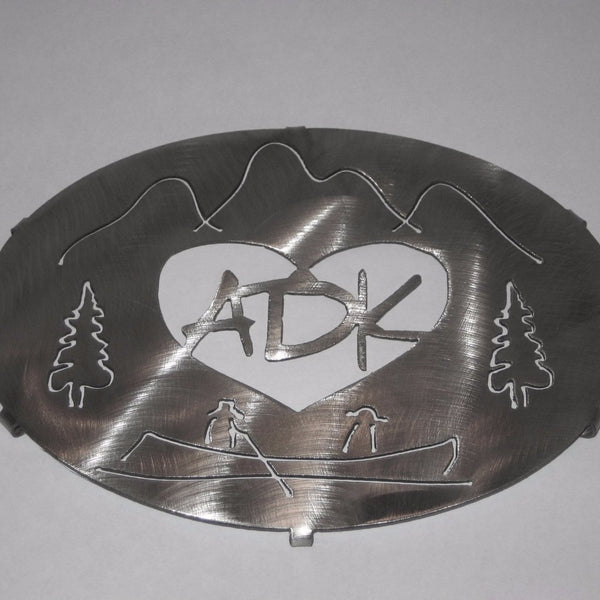 ADK in a heart with the Adirondack mountains, trees and guide boat.  It is stainless steel and measures 8" x 6".