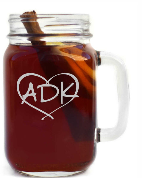 ADK in a heart logo sand blasted in white on a clear glass handled mason jar.