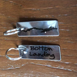 Two-sided Stainless steel keychain.  Bolton Landing text on one side; the silhouette of Lake George with a star noting the location of Bolton Landing on the other side.