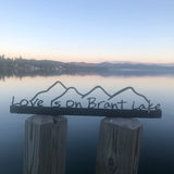Love is on Brant Lake text on a metal sign with the cutout of the Mountains; graphite.