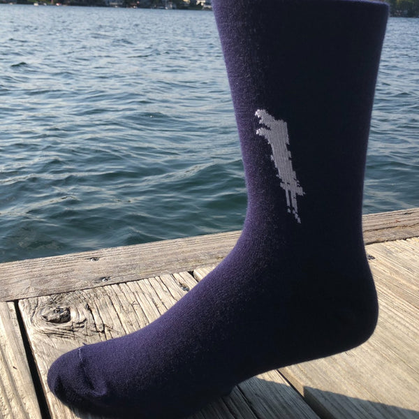 Silhouette of Brant Lake stitched in white on a unisex navy blue sock.