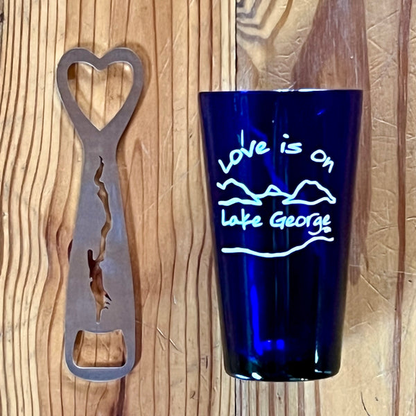 iLove is on Lake George text over our mountain/lake scene printed in white on a blue pint glass. Stainless Bottle Opener with the silhouette of Lake George cutout.
