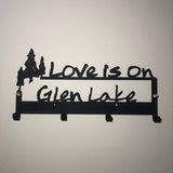 Love is on Glen Lake text on a four hook graphite wall mount with a 3 tree design.
