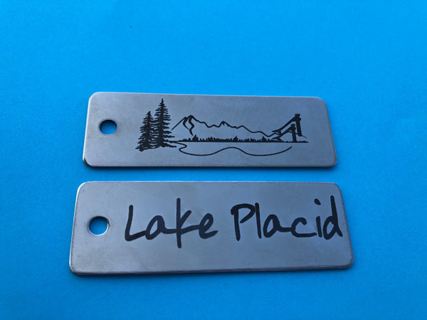 The iconic Whiteface Mountain and the Lake Placid Ski Jump  are artistically intertwined on a stainless steel key tag.  Lake Placid text on a stainless key tag with ring; key chain.