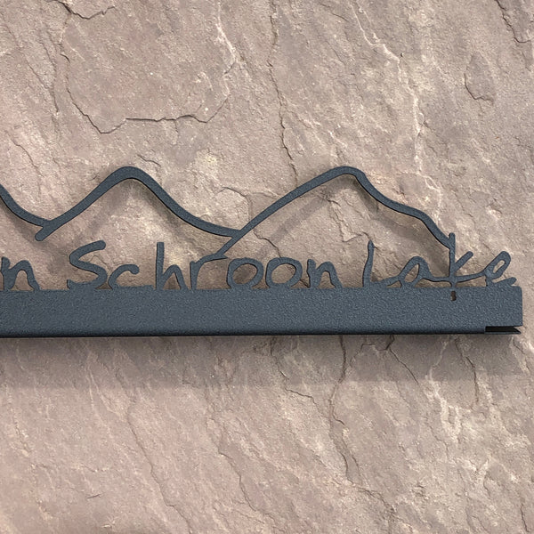Love is on Schroon Lake text with a mountain scape on a black metal sign that sits on a shelf; shelf sitter.