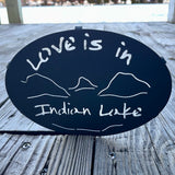 Love is in Indian Lake text  cut out  with our Lake and mountain scene on a black metal trivet.