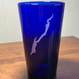 Silhouette of Lake George printed in white on a blue glass.
