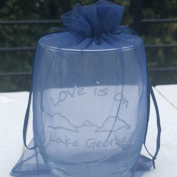 Love is on Lake George logo including the lake and mountains on a stemless wine glass packaged in a navy blue drawstring bag.