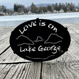 Text Love is on Lake George with the outline of the lake and surrounding Adirondack mountains; color is black.