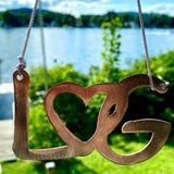 Ornament with the letters LG with an interlocking heart with a metal hanger .
