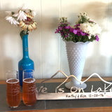Love is on Lake George Text on a metal sign with the cutout of the Mountains.  Two Love is on Lake George stemless champagne flute.