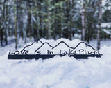 Love is in Lake Placid text on a metal sign sitter with the Adirondack mountains; color black
