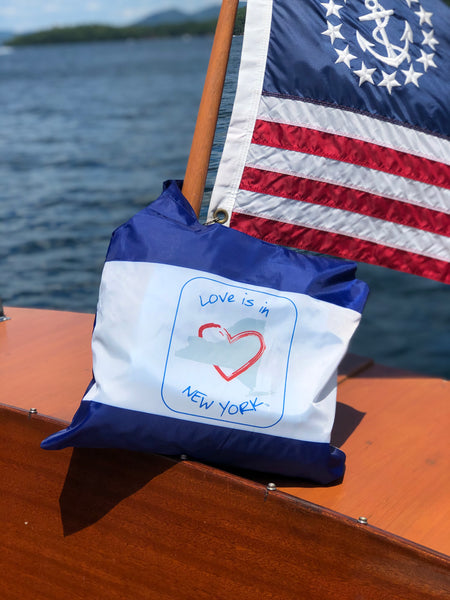 Love is in New York blue text around the map of the state of New York with a red heart. It is a blue reusable tote that holds up to 25#.