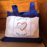 Love is in New York blue text around  the map of the state of New York with a red heart.  It is a blue reusable tote that holds up to 25#.