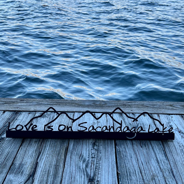 Love is on Sacandaga Lake on a black metal sign with mountains.