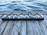 Love is on Sacandaga Lake on a black metal sign with mountains.