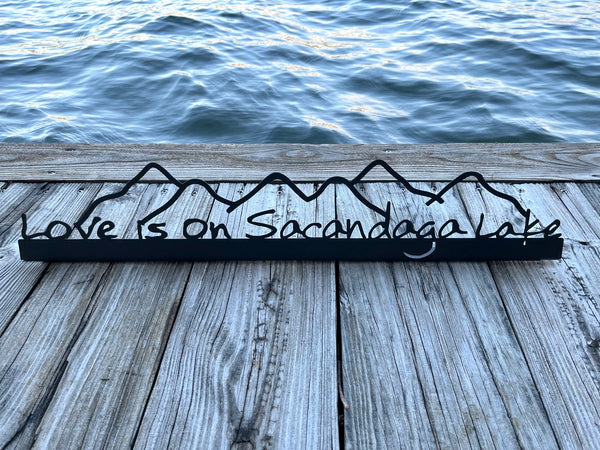 Love is on Sacandaga Lake on a black metal sign with mountains.