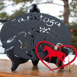 Horse in a red heart metal ornament. Saratoga text arched over a jockey riding a horse metal trivet