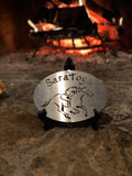 Saratoga text arched over a jockey riding a horse. Stainless Steel finish.