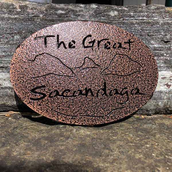 Text The Great Sacandaga with the outline of the lake and surrounding Adirondack mountains; color copper pebble.