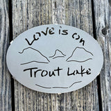 Love is on Trout Lake text over our cutout  Lake and Mountain scene on a black metal trivet.