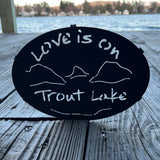 Love is on Trout Lake text over our cutout  Lake and Mountain scene on a black metal trivet.